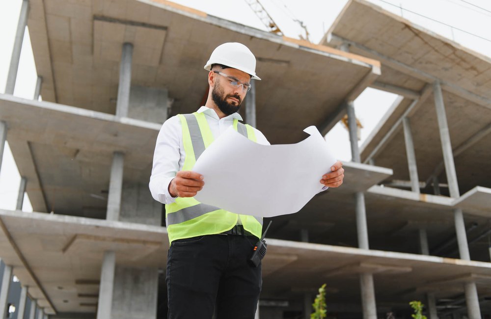 Construction professional examining blueprints on site during a forensic review