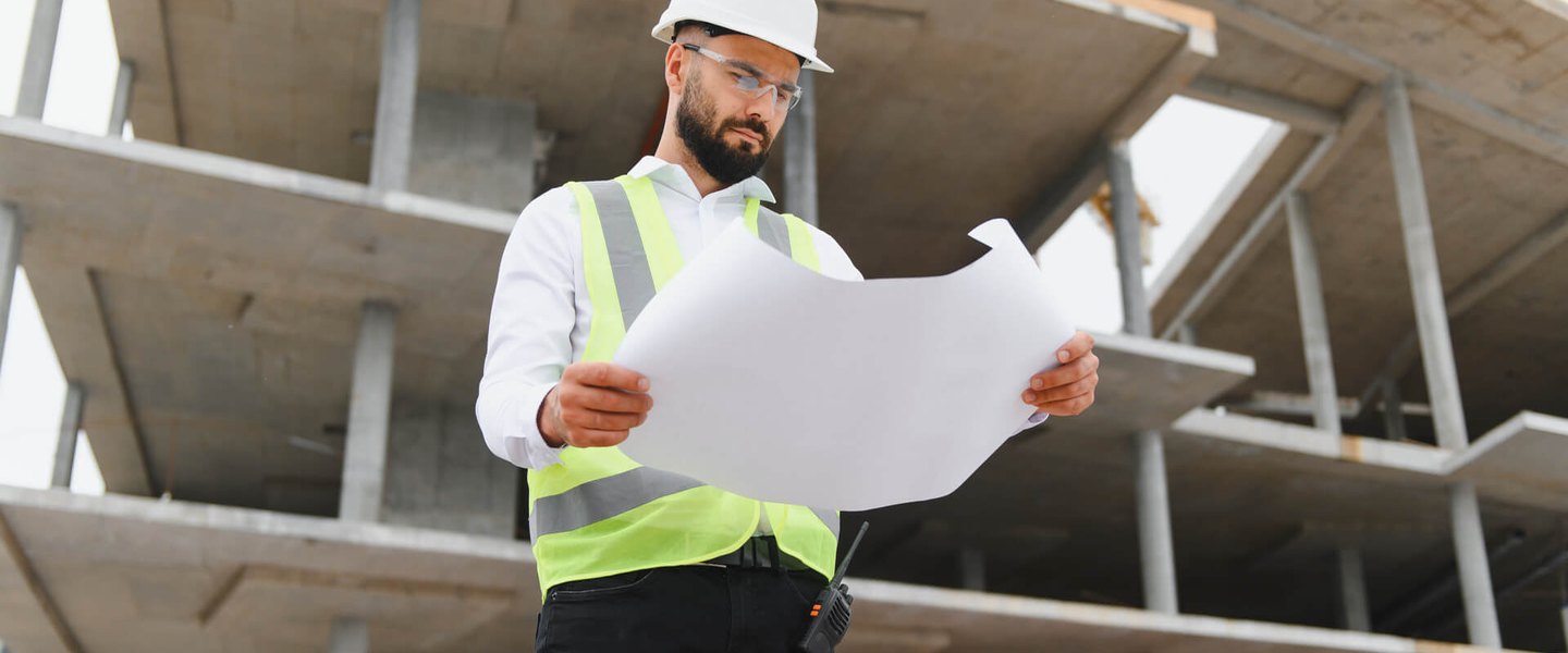 Construction professional examining blueprints on site during a forensic review