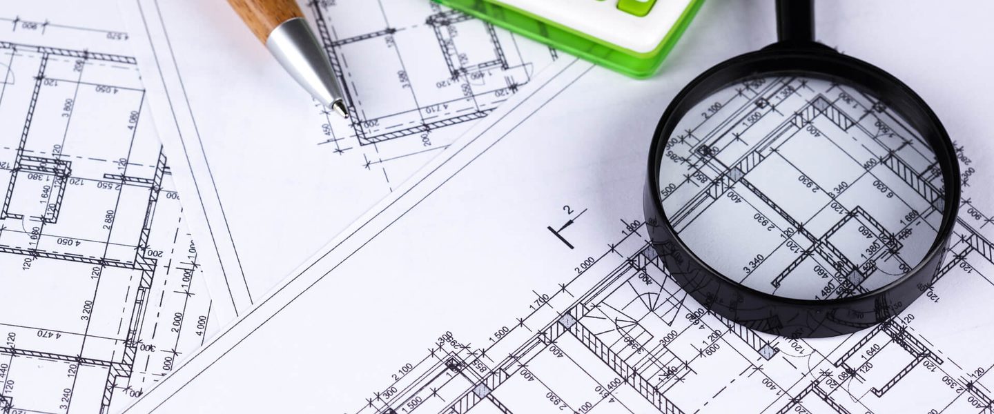 Magnifying glass and calculator over construction drawings during a quality-control review